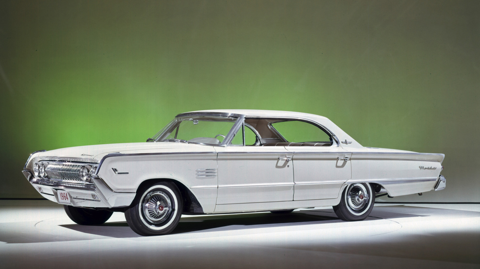 Білосніжний Mercury Marauder 1964 року на білому подіумі в студії із зеленою підсвіткою позаду.
