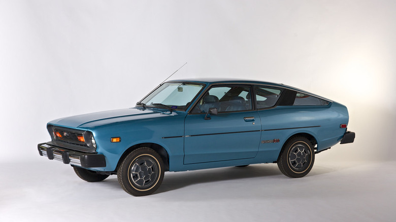 Світло-блакитний металік Datsun B210 fastback hatchback coupe 1970-х років, ізольований на простому білому фоні.