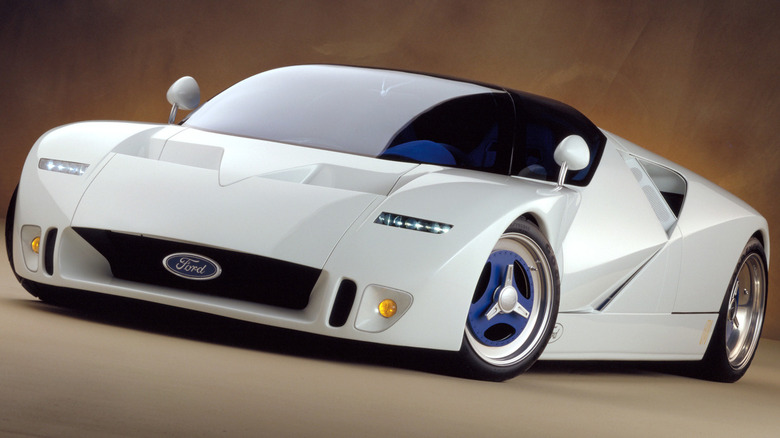 Білий концепт-суперкар 1995 Ford GT90, що демонструє його кутастий дизайн New Edge, гострі трикутні бічні отвори, низький перед з центральною емблемою Ford та сині триспицеві диски.