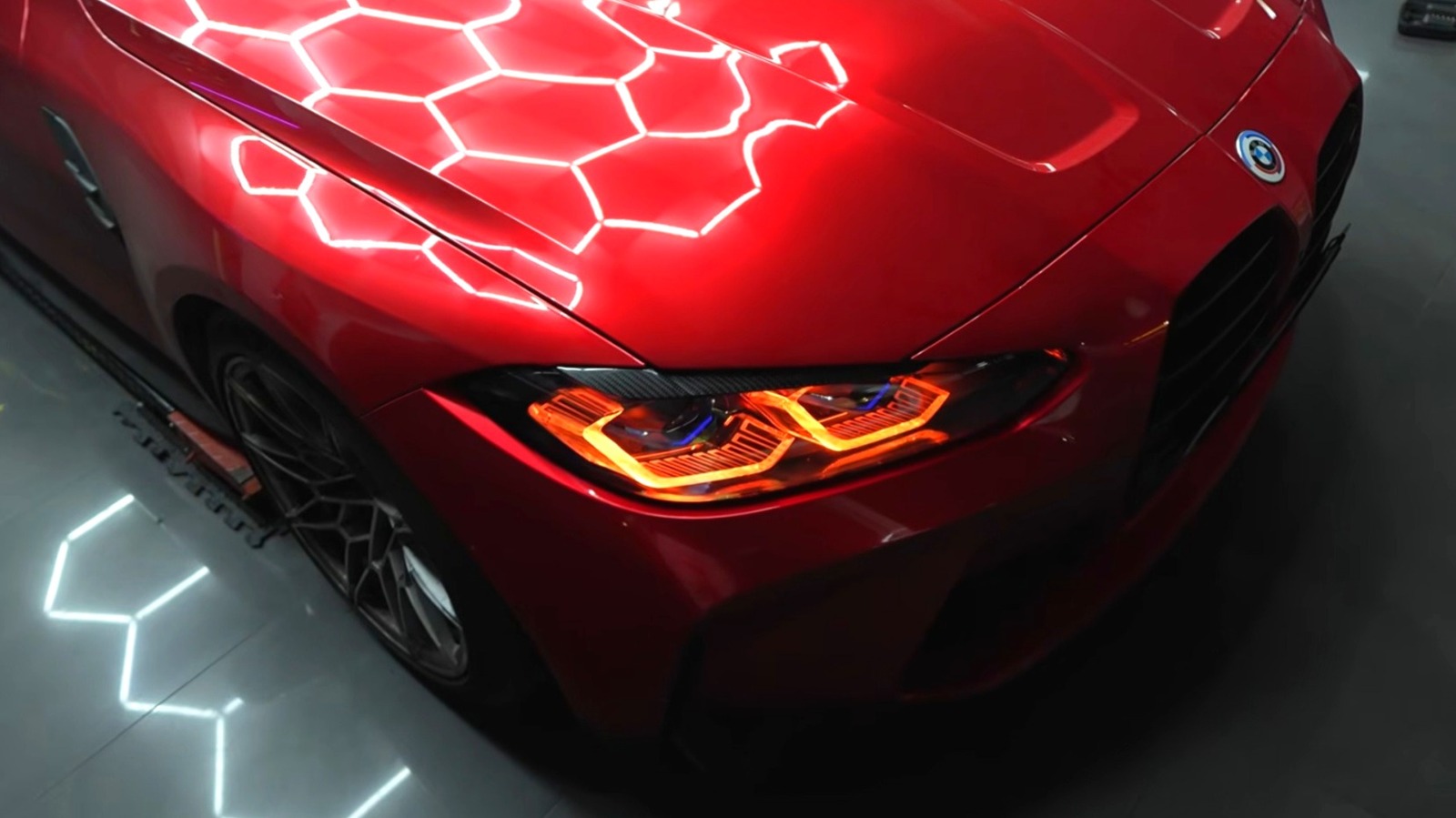 Червоний BMW M4 з червоними фарами у гаражі з шестикутною підсвіткою
