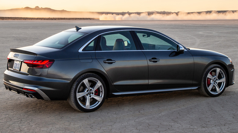 Сірий Audi S4 на ґрунтовій поверхні з пагорбами на задньому плані.