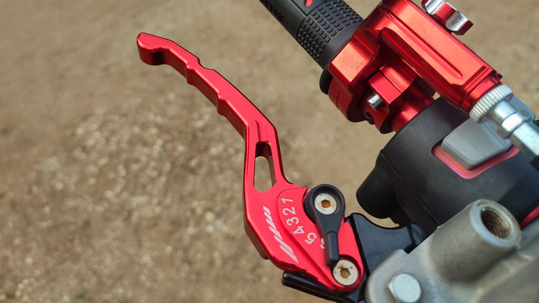 A motorcycle's adjustable hand brake in red.
