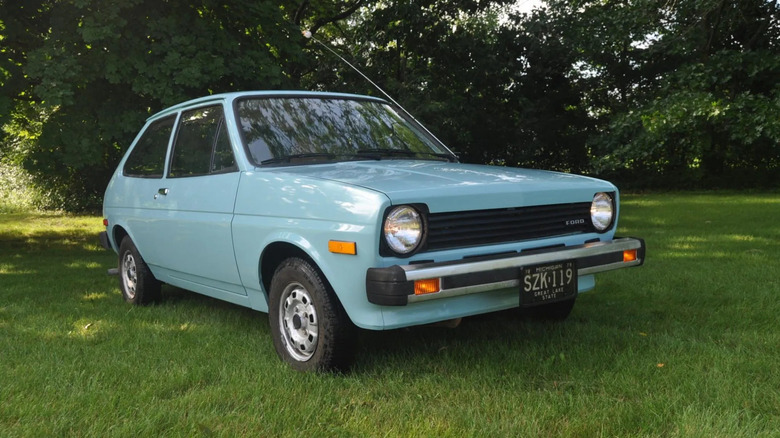 Пудрово-блакитна Ford Fiesta 1980 року, припаркована на траві перед деревами