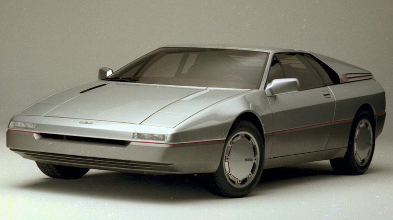 Концепт 1984 Ford Maya від Italdesign Giugiaro, що демонструє його сріблястий клиноподібний профіль, низький ніс з утопленими фарами та аеродинамічні ковпаки коліс, що щільно прилягають.