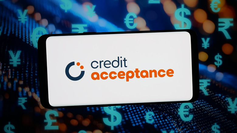 У цій ілюстрації логотип американської автофінансової компанії Credit Acceptance відображається на смартфоні на абстрактному фоні екрану комп'ютера.