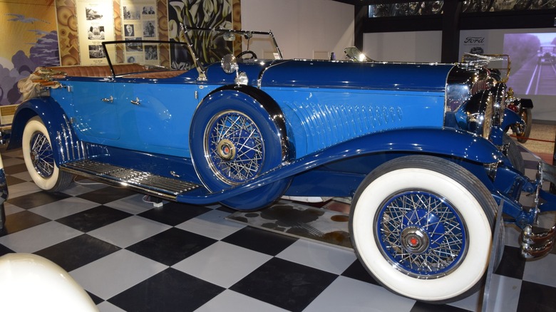 Синій Duesenberg Model J 1931 року, припаркований на шаховій підлозі в автомобільному музеї
