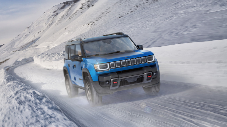 Металево-синій Jeep Recon 2026 року їде дорогою, вкритою снігом, у горах.