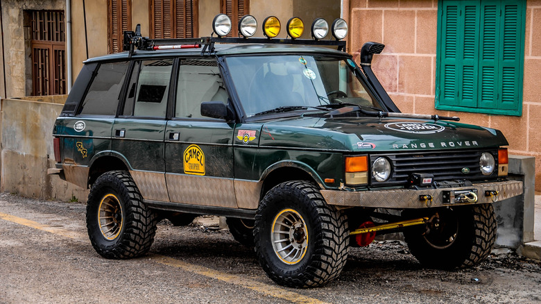 Темно-зелений модифікований позашляховик Range Rover Classic перед будівлею