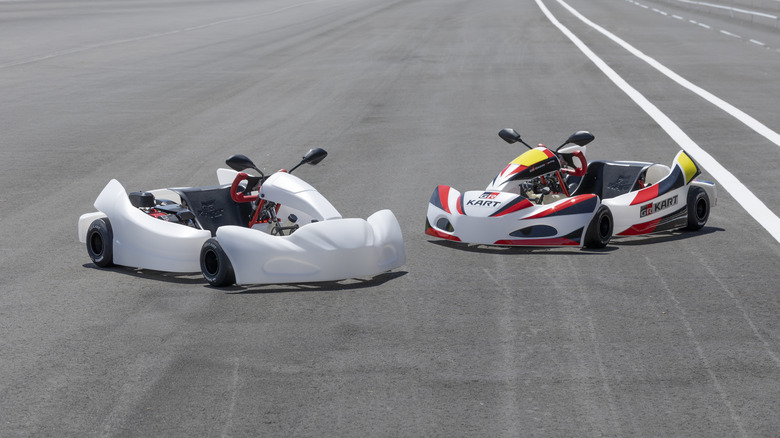 Два картинги Toyota GR Kart, припарковані поруч. Лівий карт має білу панель без логотипів, а правий – червоно-чорні наліпки GR.