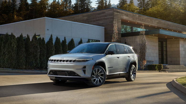 Сріблястий Jeep Wagoneer S на під'їзній дорозі біля сучасного будинку.