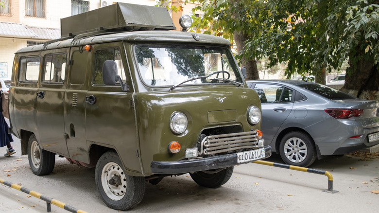 Оливково-зелений фургон UAZ-452 для бездоріжжя, припаркований на вулиці.