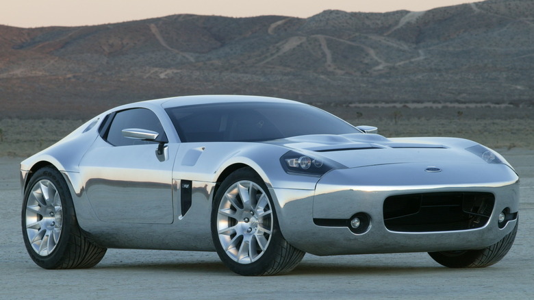 Концепт-купе 2004 Ford Shelby GR-1 у повністю дзеркальному оголеному алюмінієвому виконанні, що демонструє його довгий скульптурний капот, помітний повітрозабірник решітки та профіль Kamm-tail на відкритому пустельному плато.