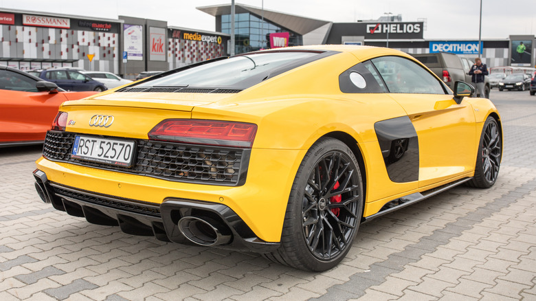 Жовтий Audi R8 RWD ззаду під кутом на громадській парковці.