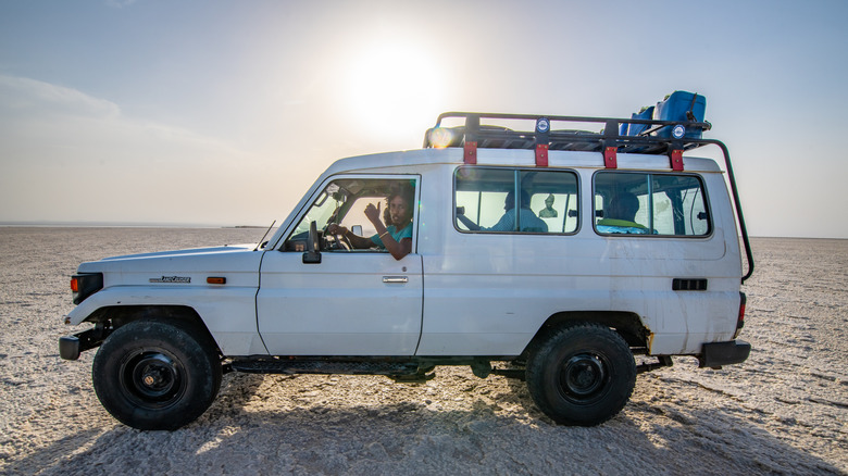 Білий Toyota Land Cruiser проїжджає пустелею.