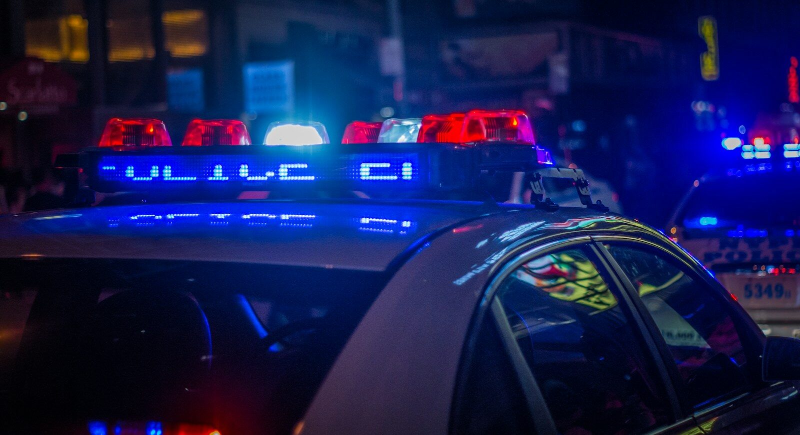 Поліцейський автомобіль з увімкненими червоними та синіми аварійними вогнями на міській вулиці