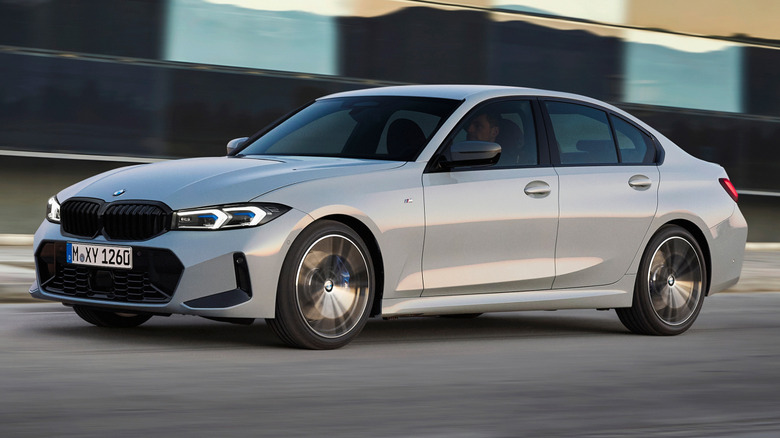 Сірий BMW 3 Series в русі перед будівлею.