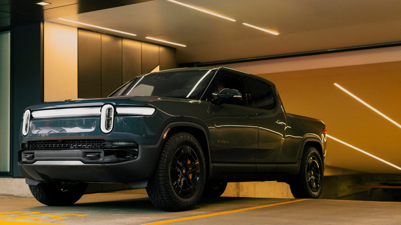 Синій Rivian R1T виїжджає з паркувального гаража.