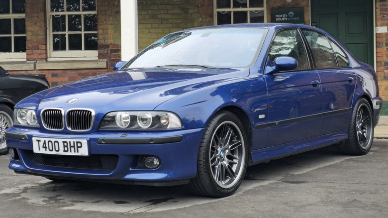 Синій E39 BMW M5, припаркований перед будівлею.