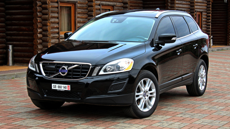 Чорний Volvo XC60 2012 року, припаркований біля дерев'яних будівель.