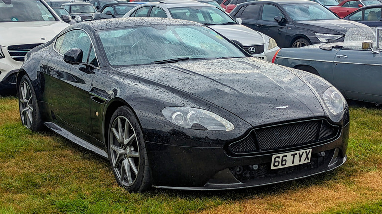 Чорний Aston Martin V8 Vantage 2012 року, припаркований на траві.