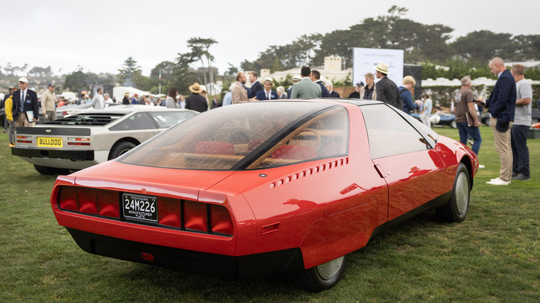 Червоний Ford 1979 року на виставці Pebble Beach Concours D'Elegance з численними людьми та іншими автомобілями на задньому плані