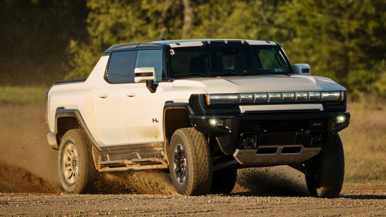 Білий пікап GMC Hummer EV 2022 року в русі по бездоріжжю.