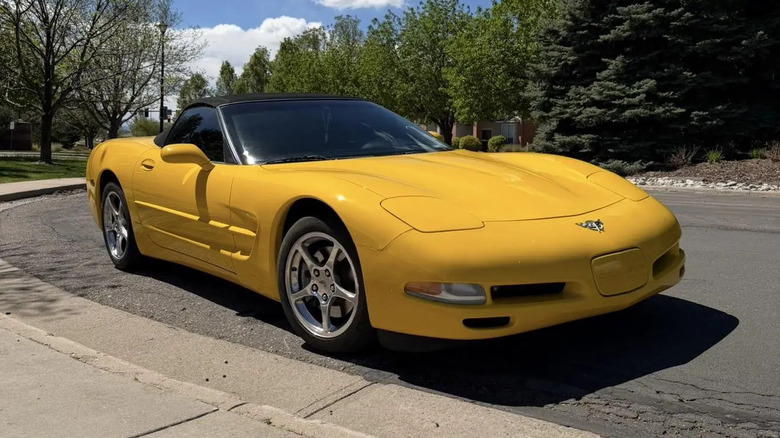 Жовтий кабріолет Corvette C5, припаркований на узбіччі дороги перед деревами