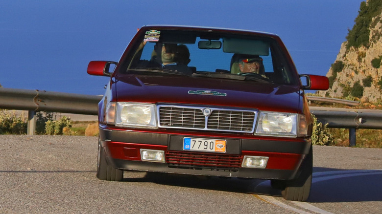 Темно-червоний Lancia Thema 8.32 проходить поворот під час гірської гонки в Греції