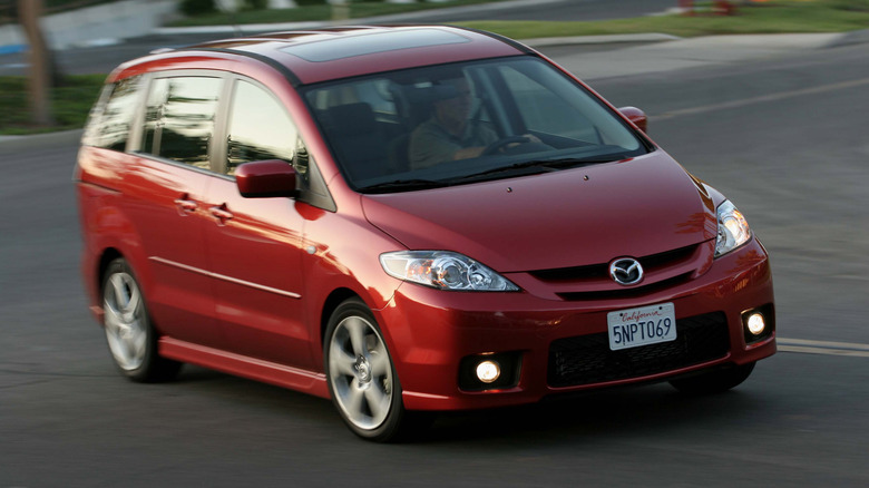Темно-червоний Mazda5 першого покоління, що проїжджає поворот із увімкненими протитуманними фарами