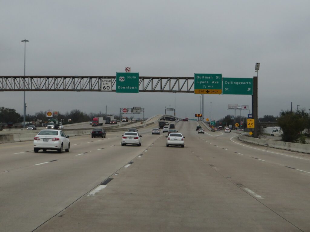 Traffic on a multi-lane stretch of US 59 under overhead highway signs