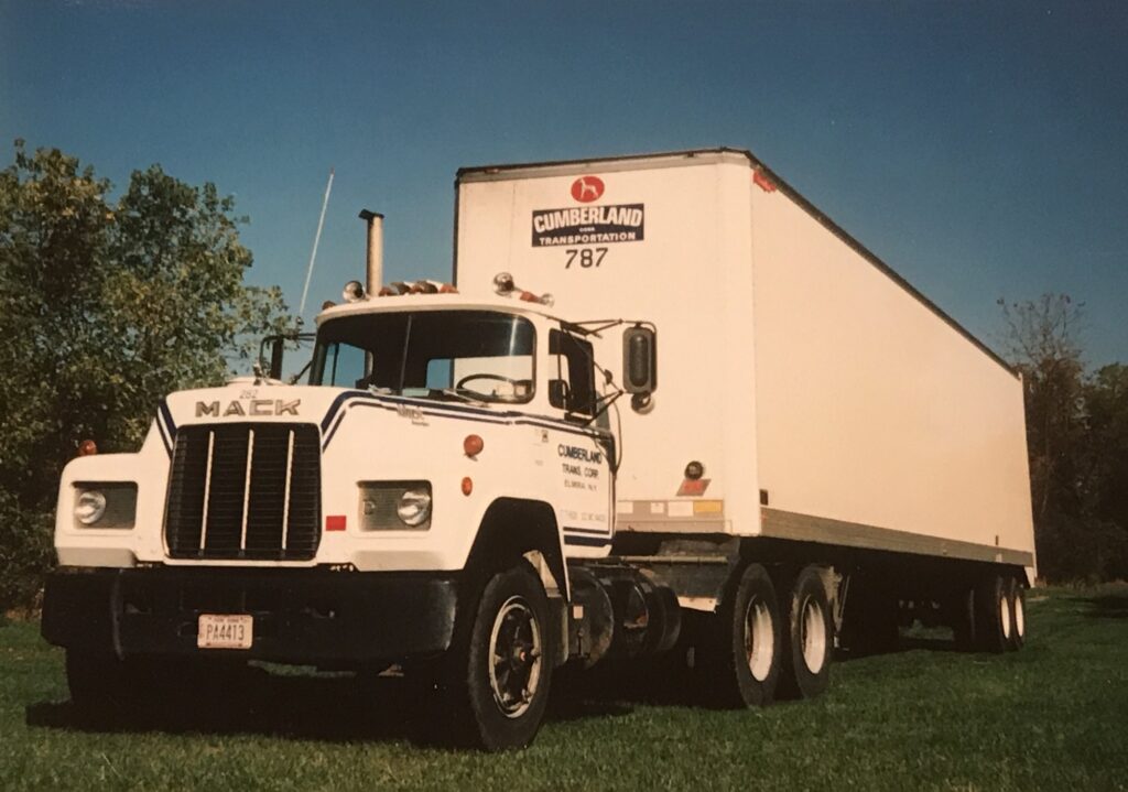 White Mack semi-truck with a trailer parked on grass
