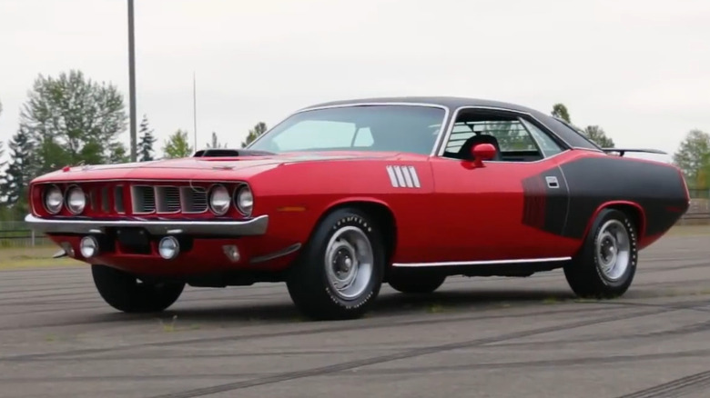 Червоний Plymouth Hemi 'Cuda 1971 року з чорними наліпками та капотом-шноркелем на асфальтовій доріжці.