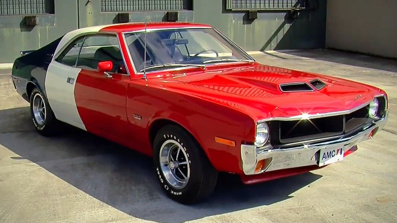 American Motors Javelin 1970 року в червоно-біло-синьому гоночному ліврей, припаркований на бетонному майданчику.
